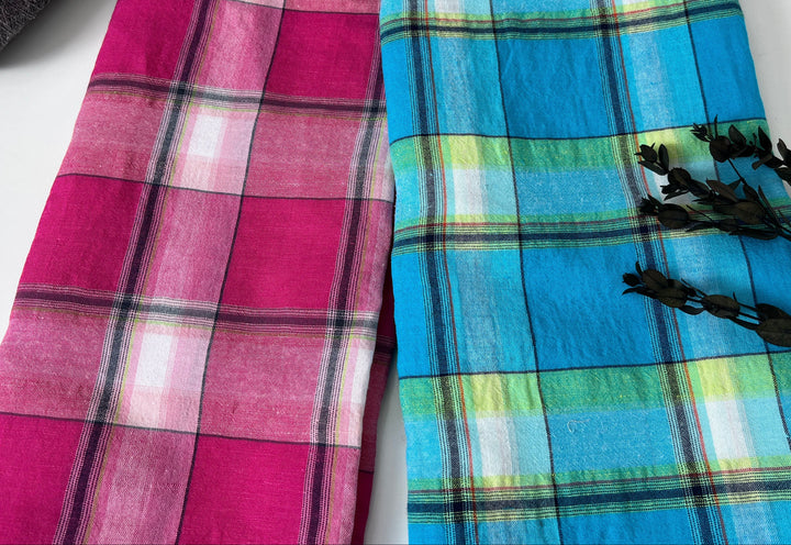 Two plaid scarves, one pink and purple, the other blue and green, on a white surface.